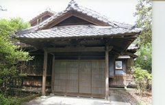 敷地内に樹木が生えている、黒木家住宅の瓦葺の玄関を写した写真