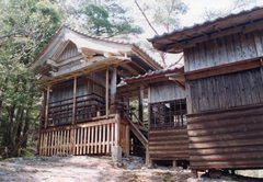木材で建築された年季の入った神社の本殿を左側から撮影した写真