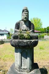 石碑の上に人を象った石が設置されている写真