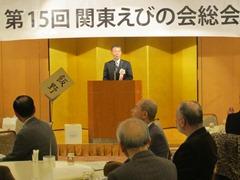 演台前に立ち話をしている男性とテーブルの椅子に座って男性の話を聞いている参加者の写真