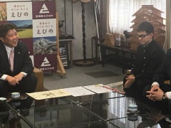 テーブルを囲んで椅子に座り笑顔で話をしている中武くんと市長の写真