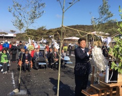 市長が関係者達の前で紙垂の様な白い紙を紐に結んでいる写真