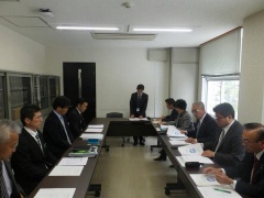 長机が長方形を作るように並んでいて、周りに関係者達が座って会議をしている写真