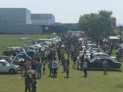 芝生の空き地の両側に車が停まっていて、車の間をお客さん達が歩いているカーフェスタ会場の写真