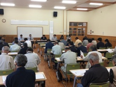 奥にはホワイトボード、手前には話を聞いている参加者たちの後ろ姿が写っている写真