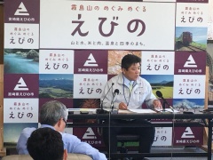 えびのと書かれた壁の前で市長が座って資料を見ながら話をしている写真