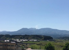 青空の下にえびの高原、手前には民家や畑が写っている風景写真