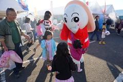 えびの市マスコットキャラクターみなほちゃんを囲む親子の写真