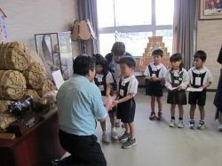両ひざをついて目線の高さを園児にあわせた市長が、市内幼稚園の園児から義援金を受け取っている写真
