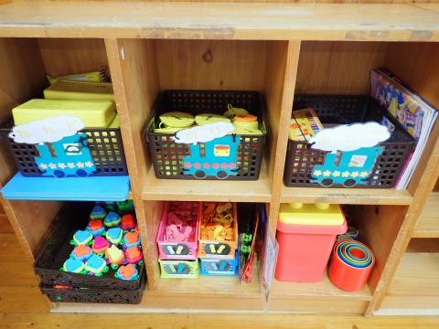えびの市地域子育て支援センターに設置されている合計6個の収納スペースがある棚とそこに収納されたたくさんのおもちゃを写した写真
