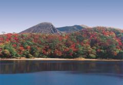 池の水がコバルトブルー色をしている六観音御池の周りの木々が紅葉し、後方に韓国岳が見えている写真
