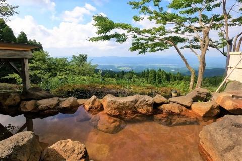 岩で囲われた露天風呂から遠くに緑の木々が見渡せる展望露天風呂の写真