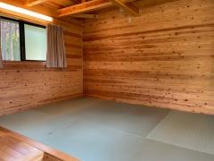 木造づくりの室内で、カーテン付きの小さな窓があり、若草色の畳のスペースがある5人用ケビンの室内写真