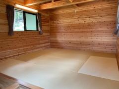 木造づくりの室内で、カーテン付きの小さな窓があり、白茶色の畳のスペースがある8人用ケビンの室内写真
