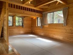 木造づくりの室内で、カーテン付きの小さな窓が複数あり、白茶色の畳のスペースがある12人用ケビンの室内写真