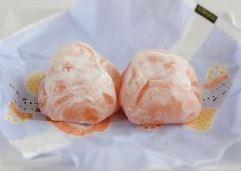 オレンジ色の餅に粉砂糖がまぶしてある宮崎たまたま(餅)が包装紙の上に置いてある写真