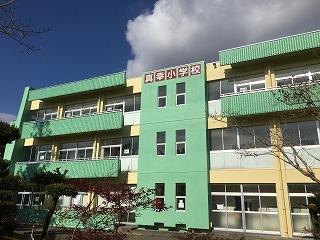 白い雲と青い空を背景に緑の外壁で構成された校舎を撮影した写真