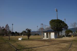 フェンスの手前にトイレや動物の遊具が設置されている運動公園の写真