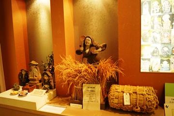 米俵や稲穂、4つの田の神さあの石像が展示されている写真
