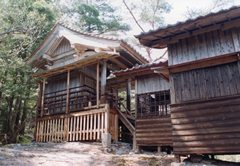 木材で建築された年季の入った神社の本殿を左側から撮影した写真