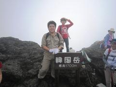 韓国岳標高1700メートルと書かれた札の横でえびの市長が笑顔で立っている写真