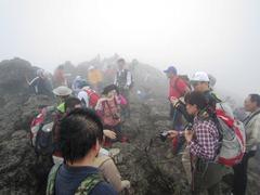 霞みがかっている岩山をリュックを背負った沢山の登山者たちが歩いている写真