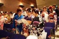 成人した振り袖姿の3名の女性たちが式次第を見ながら話をしている写真