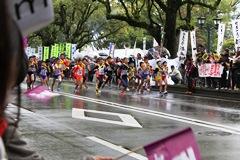 雨で路面が濡れている道路を選手たちが走っている様子が写っている写真