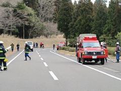 道路脇に消防車を停め防災訓練をしている消防団員や警察官の写真