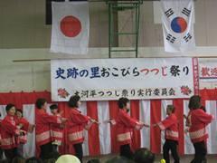 日本と韓国の国旗の下で赤い法被を着て踊っている参加者の写真
