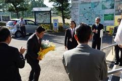 拍手の中、花束を持った市長が頭を下げながら歩いている写真