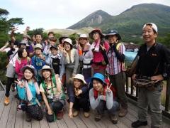 山をバックにポーズをとって並ぶ、山ガールサミットinえびの高原参加の女性たちや関係者の記念写真