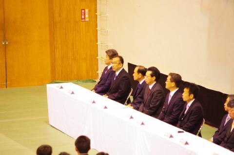 飯野高等学校入学式の来賓席に座っている男性8名の写真