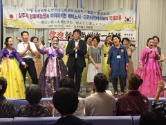 ステージ上で、韓国の民族衣装を着ている数名の女性や拍手をしている市長の写真