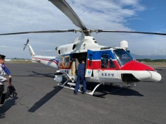 白をベースに赤や青のデザインがされた着陸しているヘリコプターの写真