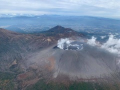 山の火口から煙が出ている様子を上空から撮影した写真