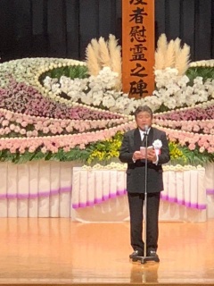 ステージ上に設置された花祭壇の前で市長が式辞を述べている写真