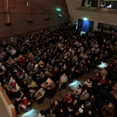 薄暗いホールの観客席が満席になっている様子を上階から写している写真
