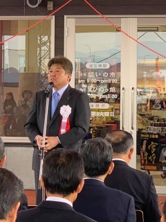 白い胸章をつけた市長がマイクスタンドの前で話をしているリニューアルオープン式典の様子の写真