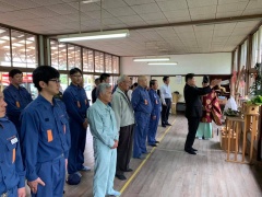 神棚の前で手を合わせている市長と青い作業着を着ている消防団員の方々が整列して神事に参加している写真