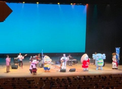 青色の背景のステージ上で楽器を演奏している大野勇太さんとバンドメンバーと、みなほやぼんちくんなどのマスコットキャラクター5体の写真