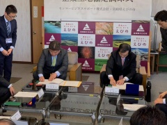 ソファに着席し、協定書に判を押している市長とセンコービジネスサポート株式会社の代表者の男性、その様子を横で見ている2名の男性の写真