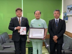 目録を持っている市長と感謝状を持っている林田先生、スーツの男性の3名が並んで立っている写真