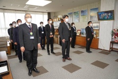 一定の距離を等間隔で開け、3列に並んで立っているスーツを着た職員の写真