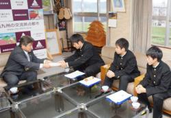飯野高校の男子学生一人が頭を下げながらえびの市長に提案書を渡している写真