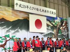 日本国旗の下で赤い法被を着た多数の男性が集まっている写真