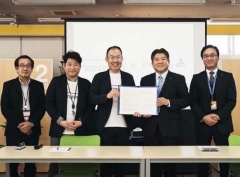 市長と村岡さんが二人で協定書を持っていて、横に関係者3人が並んでいる写真