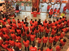赤いジャケットを着た職員が演台に立つ市長に注目している写真