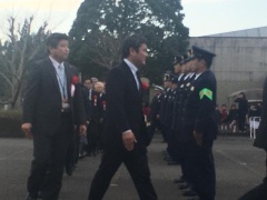 右側に整列する警察官たち、左側を市長や関係者達が縦に並んで歩いている写真