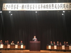 舞台中央の講演台に市長が立って話をしており、両脇に関係者たちが座っている写真